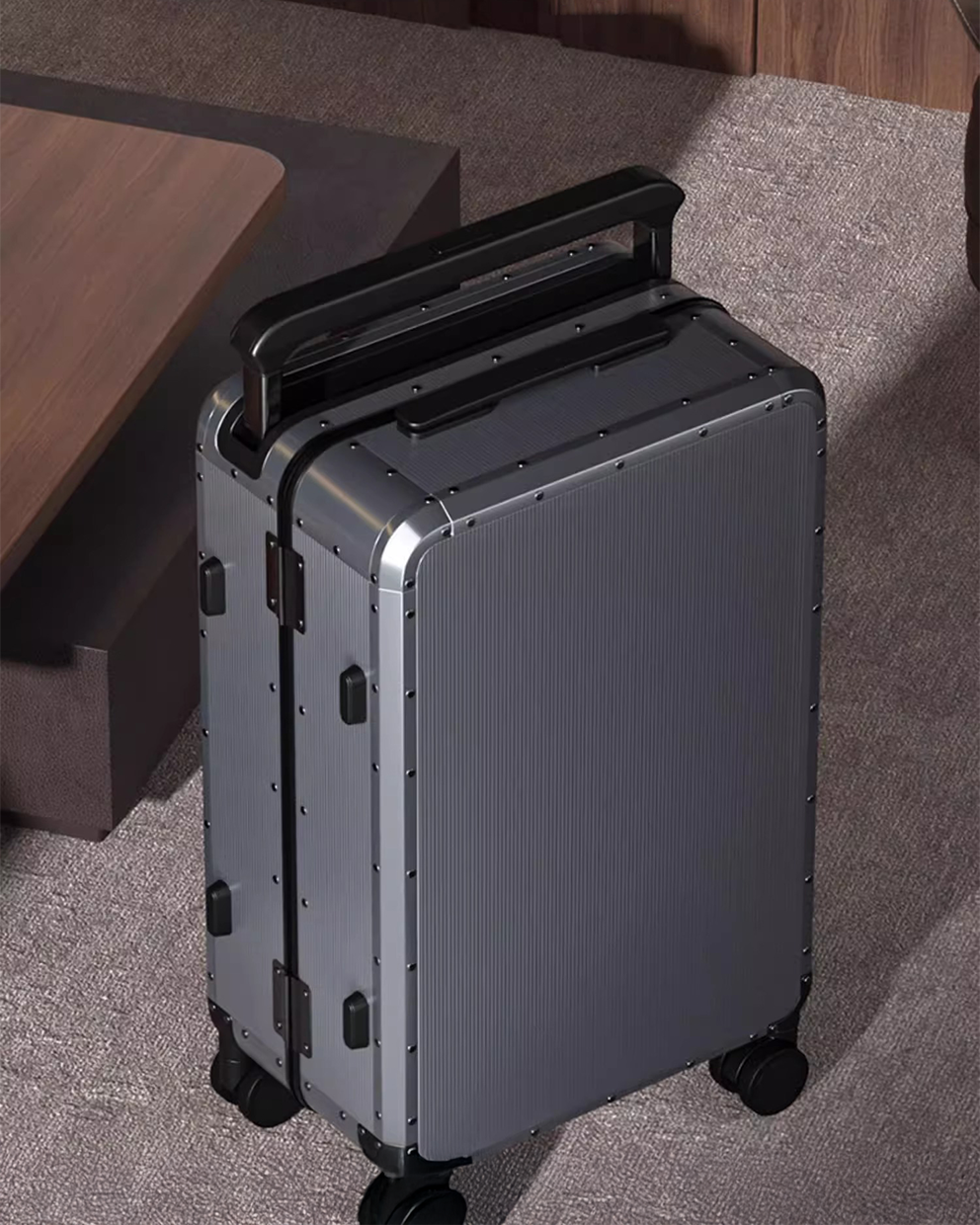 Silver suitcase with black handle on a gray carpet