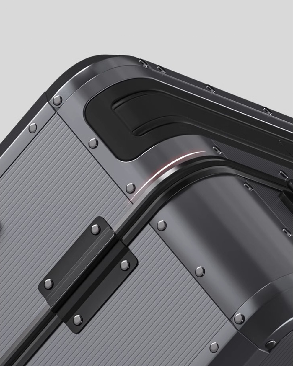 Close-up of a textured gray suitcase with metallic accents on a light gray background