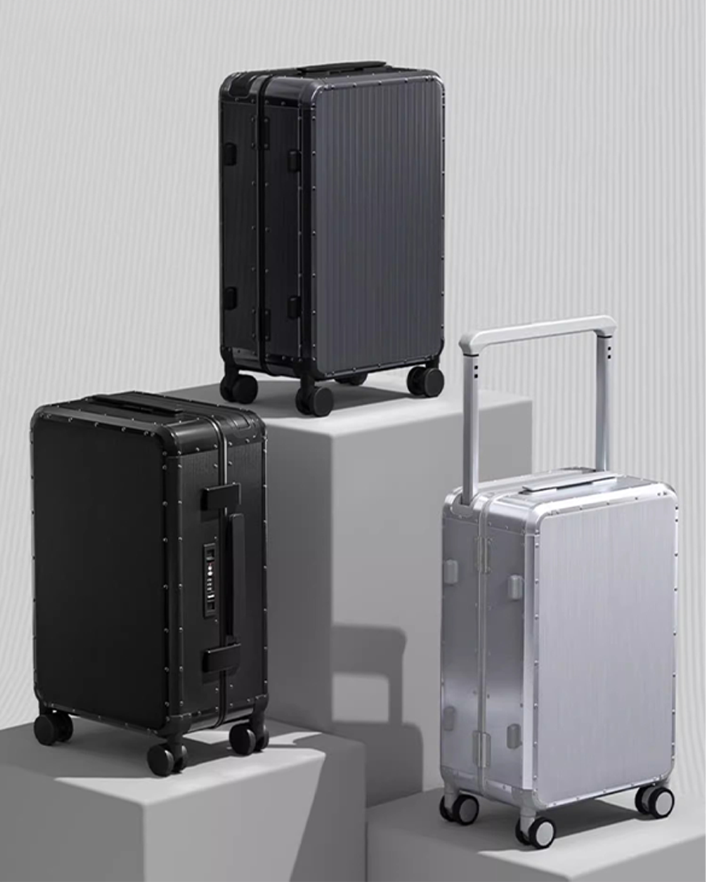 Two black suitcases and one silver suitcase on a light gray background
